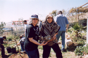 Gila and Arabiyye carry a large stone while others work in background 