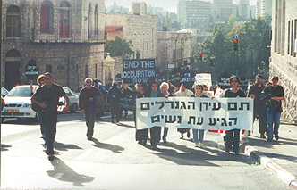 Marchers carry sign saying in Hebrew: The age of generals is over -- The time of women has begun