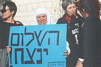 Palestinian demonstrator holds Hebrew sign saying 'Peace Will Overcome'