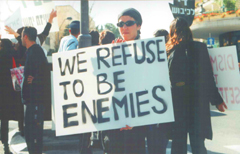 Demonstrator holds sign saying WE REFUSE TO BE ENEMIES