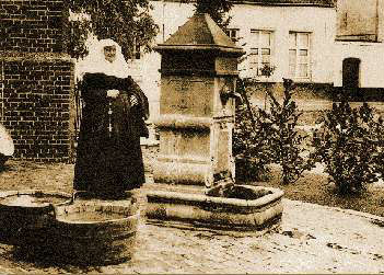 The last beguine stands by water pump in Hoogstraten, 1930